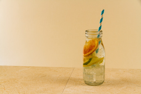 Childrenâs sparkling water drink in bottle with straw. Slices of orange, lemon and lime. Copy space on left.の写真素材
