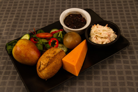 Ploughmanâs lunch with red leicester cheese, pickle, pickled onion, salad, coleslaw and bread roll and apple.の写真素材