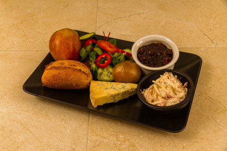 Ploughmanâs lunch with stilton cheese, pickle, pickled onion, salad, coleslaw and bread roll and apple.の写真素材