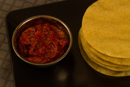 Indian poppadums stacked with bowl of lime pickle and sliced limeの写真素材
