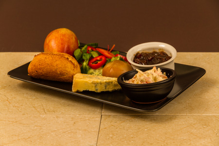 Ploughmanâs lunch with stilton cheese, pickle, pickled onion, salad, coleslaw and bread roll and apple.の写真素材
