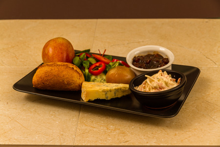 Ploughmanâs lunch with stilton cheese, pickle, pickled onion, salad, coleslaw and bread roll and apple.の写真素材
