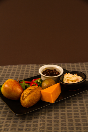 Ploughmanâs lunch with red leicester cheese, pickle, pickled onion, salad, coleslaw and bread roll and apple.の写真素材