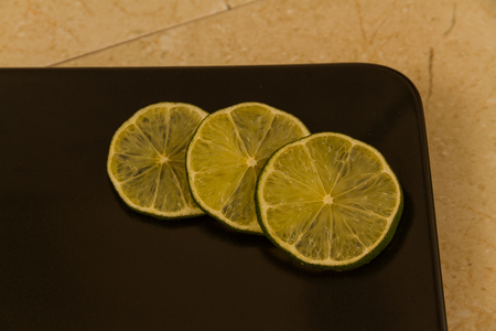 Three slices of lime spread on black background.の写真素材