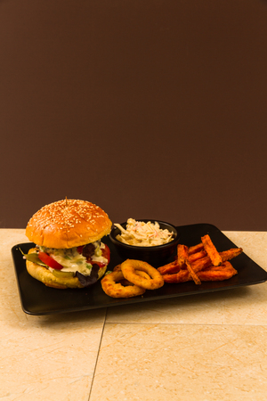 Gourmet beef burger, with salad, blue cheese sauce, sweet potato fries, onion rings and coleslawの写真素材