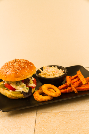 Gourmet beef burger, with salad, blue cheese sauce, sweet potato fries, onion rings and coleslawの写真素材