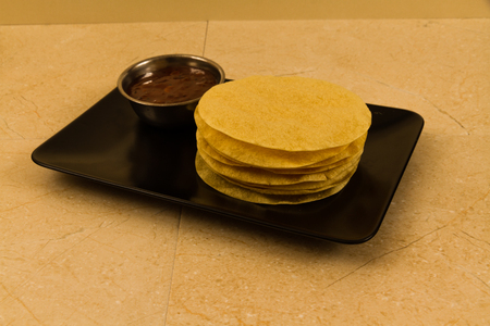 Indian poppadums stacked with bowl of mango chutneyの写真素材