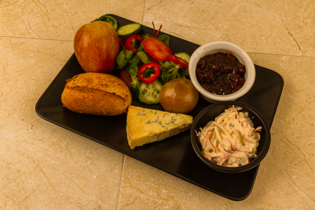Ploughmanâs lunch with stilton cheese, pickle, pickled onion, salad, coleslaw and bread roll and apple.の写真素材