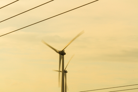 Single wind turbine with afternoon sky, framed by overhead cables.の写真素材