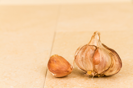 Macro of garlic bulb on pale background, one clove detached.の写真素材
