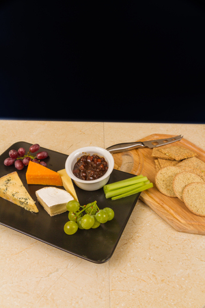 Cheeseboard, platter, cheese, red Leicester, stilton, cheddar, camembert, grapes, celery, pickle or chutney and biscuits. With copyspace.の写真素材