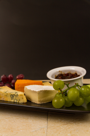 Cheeseboard, platter, cheese, red Leicester, stilton, cheddar, camembert, grapes, celery, pickle or chutney. With copyspace.の写真素材