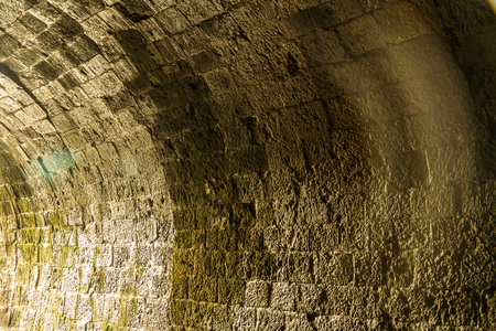 Curve and reflection of light on the bricks of a disused railway tunnel.の写真素材