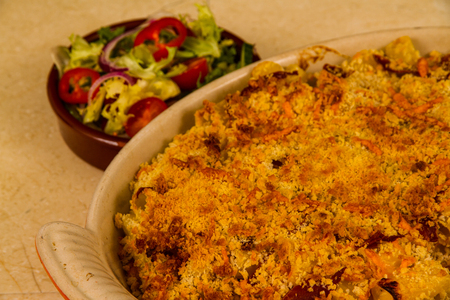 Macaroni Cheese ready to serve in ceramic dish with side salad.の写真素材