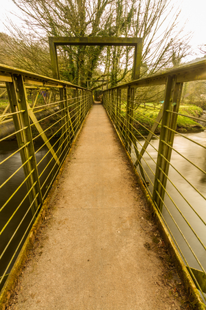 Narrow footbridge over river in early morning light.の写真素材