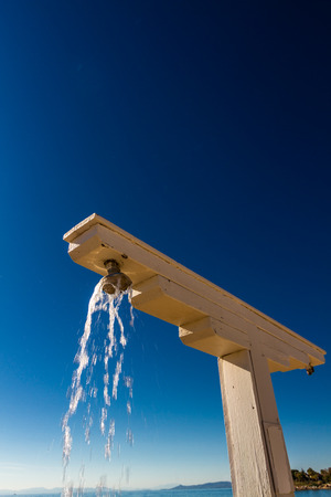 Wood beach shower flowing water against blue sky, portrait picture.の写真素材