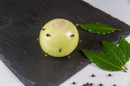 Dry Ingredients for bread sauce onion studded with cloves bay leaves and peppercorns., on slate matの写真素材