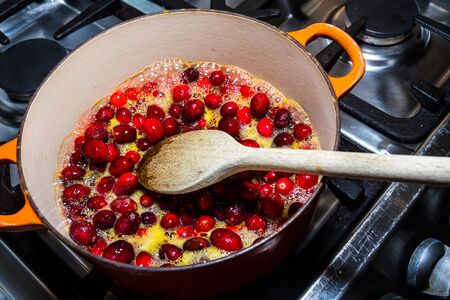 Cranberry sauce being cooked in pan, heating cranberries and orange juice.の写真素材