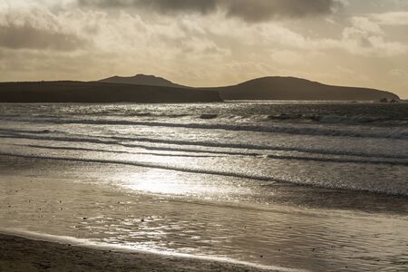 Dark back lit scene of waves on a beach, landscapeの写真素材