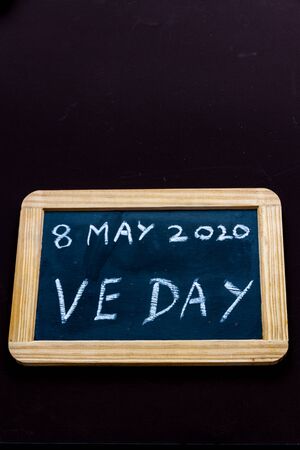 UK may bank holiday moved from 4 to 8 May 2020 to celebrate 75 years of end of WWII VE Day on old fashioned school writing slate, copyspace, portraitの写真素材