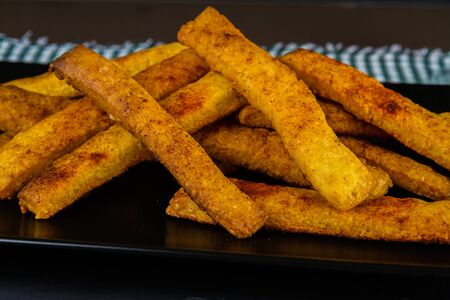 Home made cheese straws piled on  dark black landscape, side view.