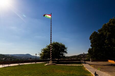 Flag of Hungary in wind on striped pole back lit by sun.の写真素材
