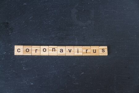 Coronavirus spelled in wooden letter blocks on dark slate background. Copyspace, landscapeの写真素材