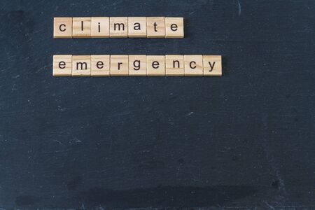 Climate Emergency spelled in wooden letter blocks on dark slate background. Copyspace.の写真素材