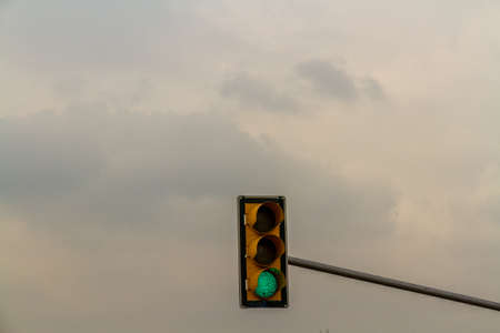 Traffic light on green, cloudy sky copyspace at top, landscape.
