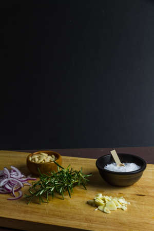 Wood wooden board with onion, rosemary, salt and pine nuts, bowl, pile,  portraitの写真素材