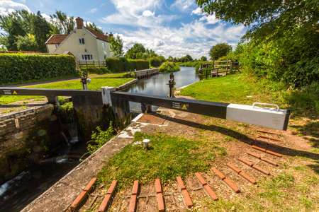Picturesque canal lock in the UK on sunny summer day. Taunton and Bridgewater Canal, Maunsel Lock, UK, wide angle.の写真素材