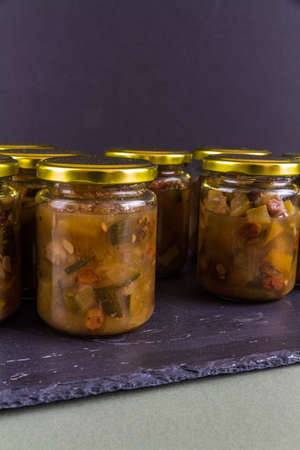 Chutney after courgette grew into marrow. Several jars black dark background portrait.の写真素材