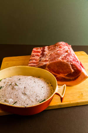 View of dish with dry cure for bacon, salt, sugar, bay leaf, pepper, juniper. On wooden chopping board, portrait with pork loin or back, copyspace at topの写真素材