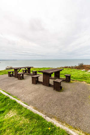 Picnic tables with sea and cliffs behind them, portrait.の写真素材