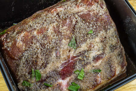 Dry salt cure on Pork loin or back joint in dry salt cure  becoming bacon with liquid brine drawn from the meat, close upの写真素材