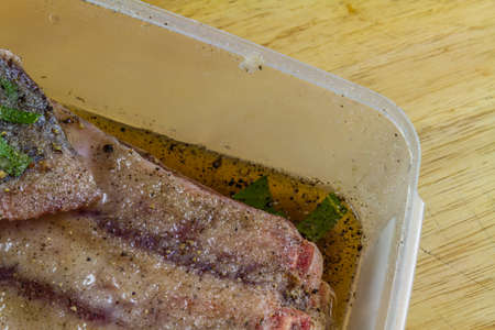 Dry salt cure on Pork belly joint in dry salt cure  becoming streaky bacon with liquid brine drawn from the meat, close up, landscapeの写真素材