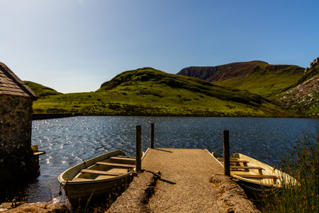 Two row boats and a small jetty on a beautiful summer day. Lake or Llyn y Dywarchen, Rhydd Du, Snowdonia or or Eryri National Park, North Wales, UK, landscapeの写真素材