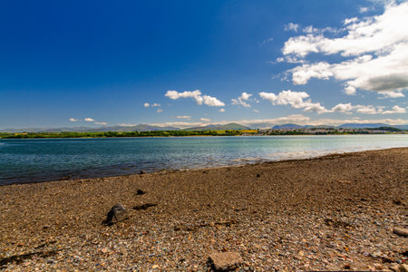 Angled View of Snowdonia or Eryri Mountains on beautiful summer day, seen from Anglesey, across the Menai Straits water, North Wales, UK.の写真素材