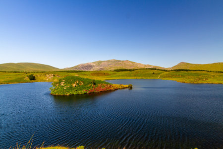 Beautiful day Snowdon or Yr Wyddfa top from Lake or Llyn y Dywarchen with island, Rhydd Du. Snowdonia or Eryri National Park, North Wales, UK, landscape, wide angleの写真素材