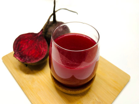 Glass of fresh beetroot juice on a wooden board, isolated on whiteの写真素材