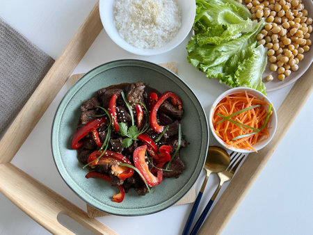 Asian food: Beef Teriyaki with red paprika and sesame seed on a plate, Assortment of vegetables and rice on the table. Beef stir fry with vegetables.の写真素材