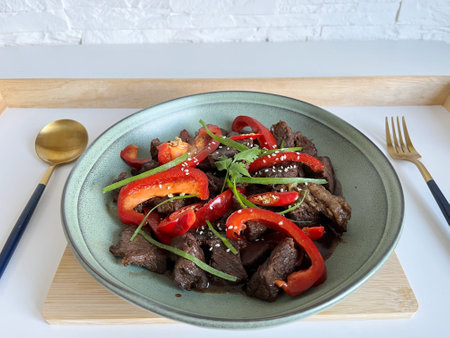 Asian food: Beef Teriyaki with red paprika and sesame seed on a plate, Assortment of vegetables and rice on the table. Beef stir fry with vegetables.の写真素材