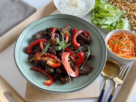 Asian food: Beef Teriyaki with red paprika and sesame seed on a plate, Assortment of vegetables and rice on the table. Beef stir fry with vegetables.の写真素材