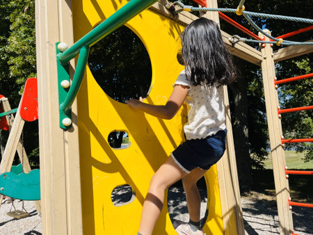 Little girl playing on a children's playground in the park in summerの写真素材