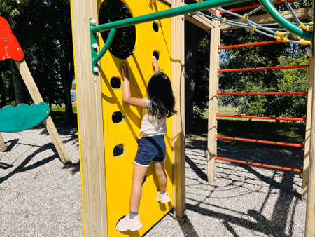 A young girl is playing on a children's playground in the park.の写真素材