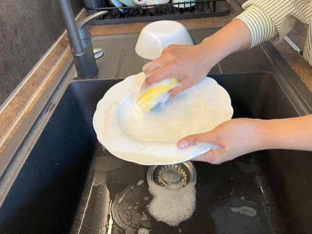 Woman washing dishes in the kitchen, close-up of hands.の写真素材