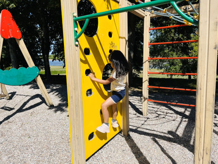 Little girl climbing on a playground in the park on a sunny dayの写真素材