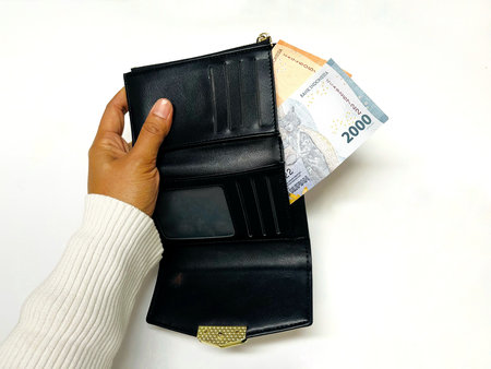 Woman hand holding wallet with money on white background. Rupiah in the wallet. Business concept.