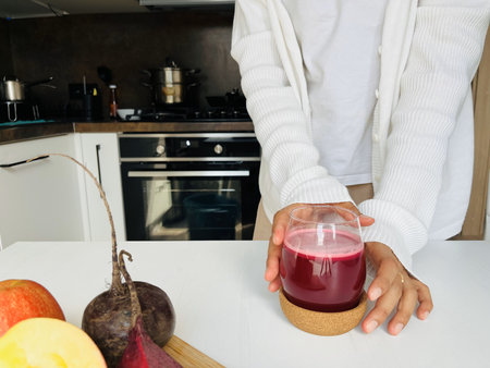 Woman grab a glass of fresh beetroot juice in the kitchen. Healthy eating concept.