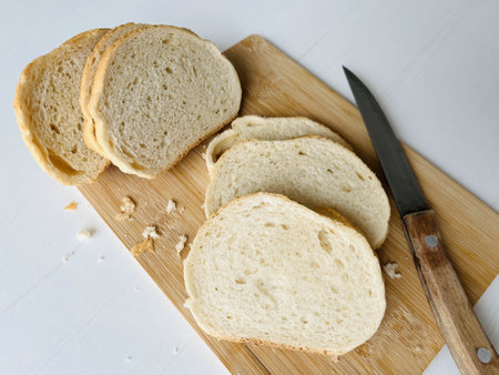 Sliced wheat bread on cutting board and knife on white backgroundの写真素材